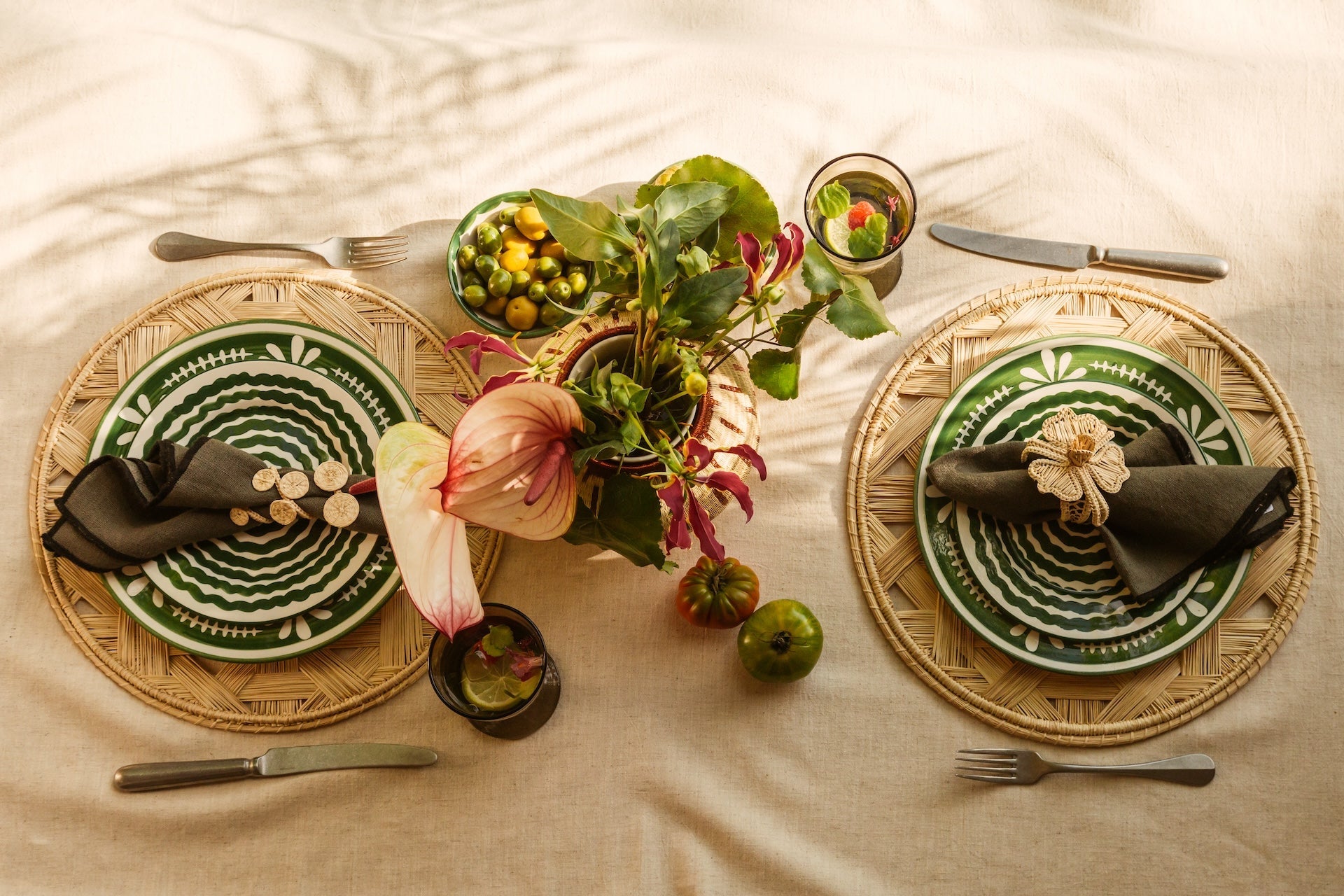 tableset in natural and green tones with handpainted plates, woven iraca placemats and a flower centrepiece