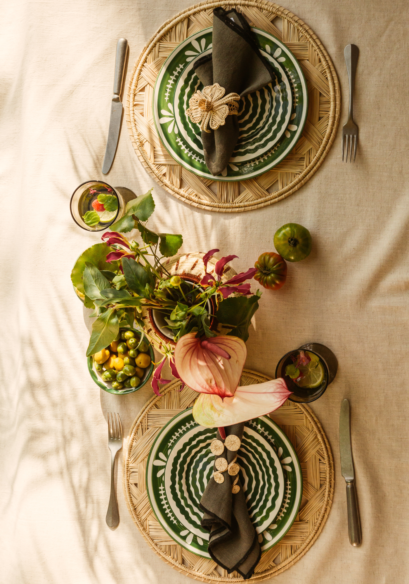 Al Fresco Breakfast tablescape featuring green hand-painted ceramics, woven palm placemats, raffia napkin rings, and a natural floral centrepiece on a linen tablecloth.