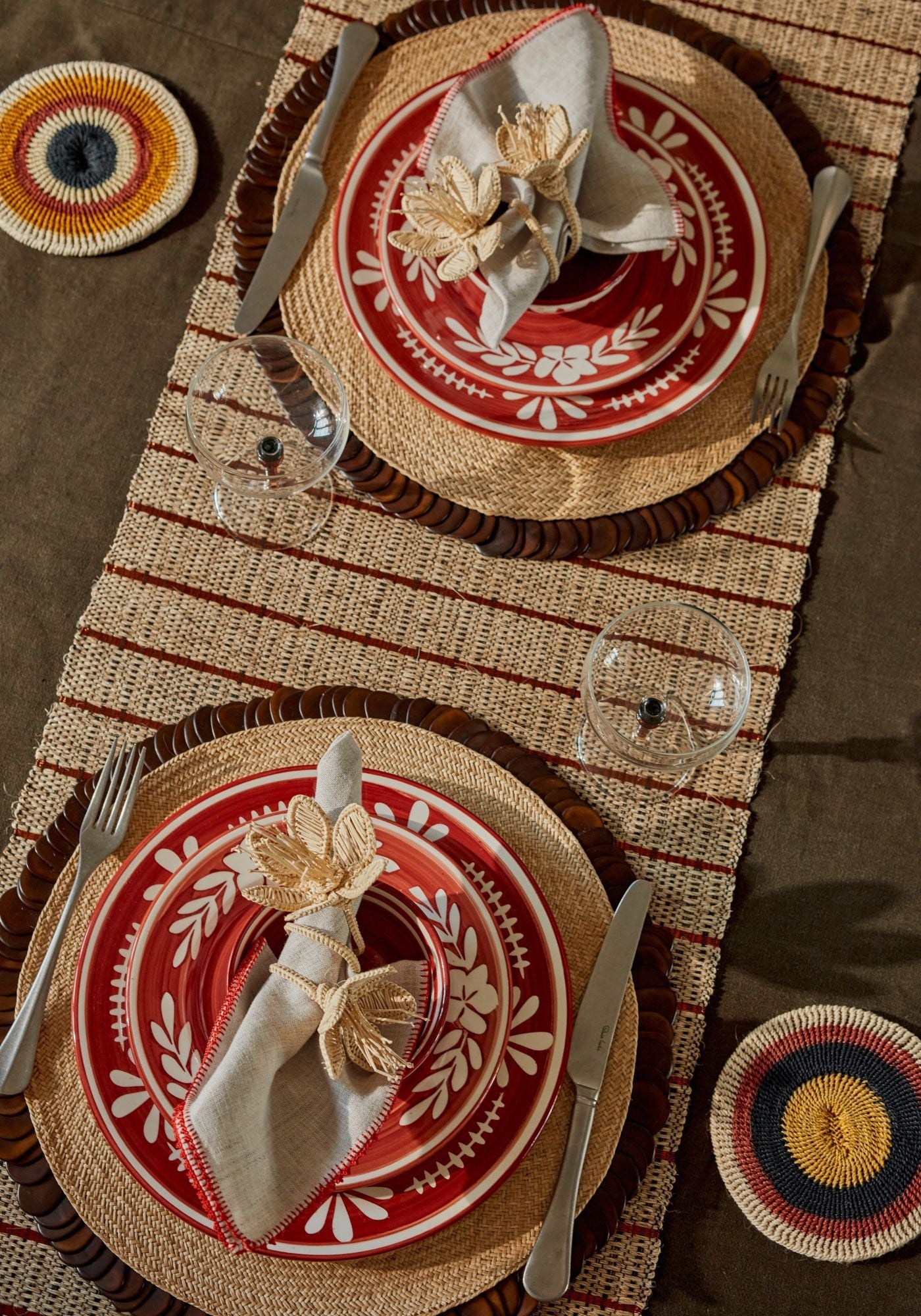 Autumn Love tablescape featuring terracotta hand-painted plates, straw-edged woven placemats, white embroidered napkins, and flower-shaped napkin rings surrounded by fruit and florals.