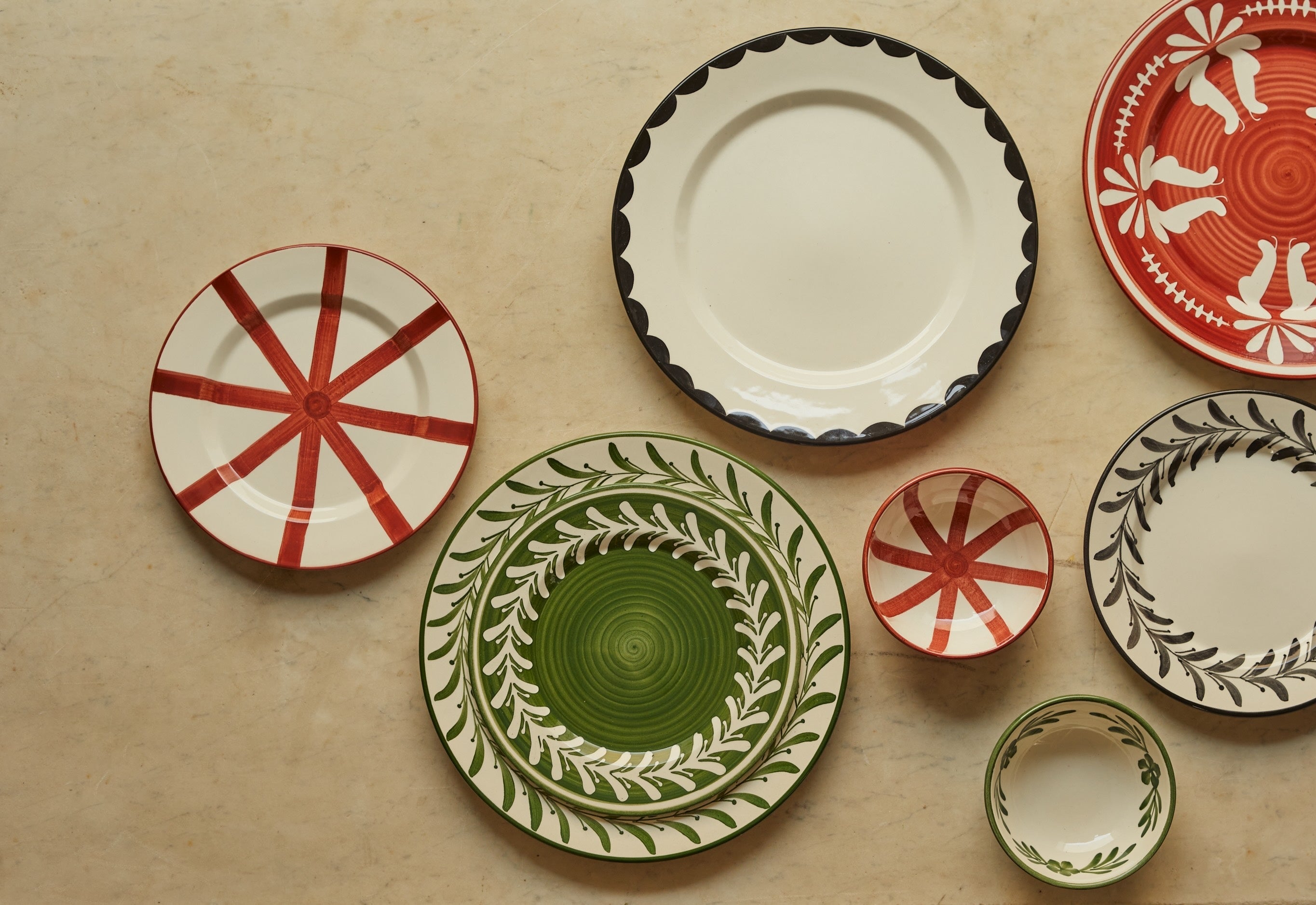 A green wall covered with artisanal plates surrounded by artisan objects 