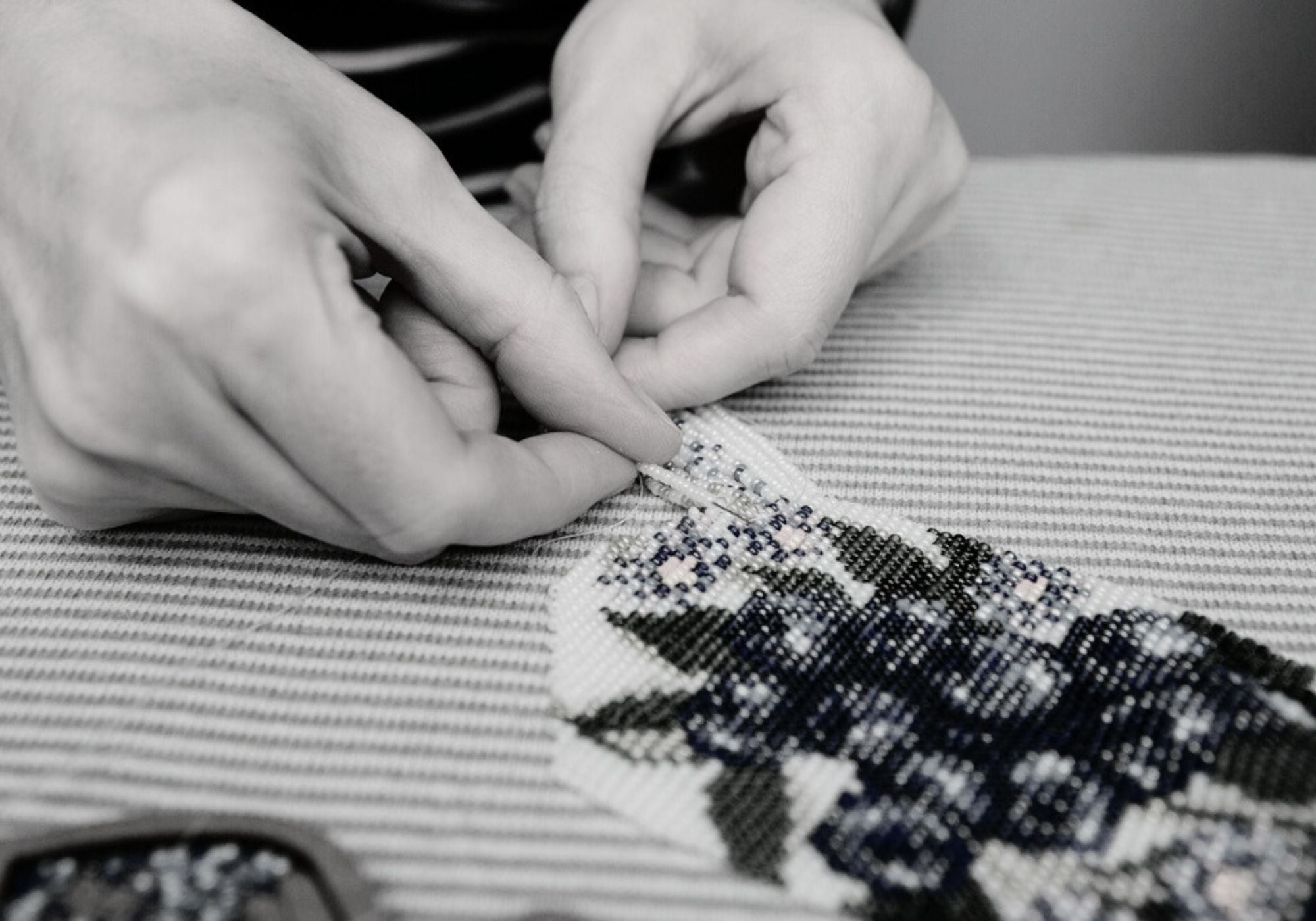 woman weaving a beaded necklace